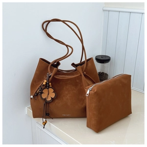 Detail view of brown suede tote bag set with floral charms and a zipper pouch