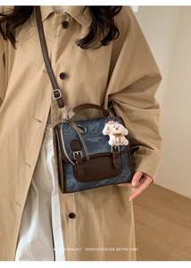 Detail view of denim blue and brown leather crossbody bag with cute puppy charm