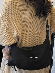 Minimalist black crescent shoulder bag in soft fabric with warm knit sweater styling