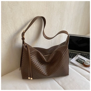Détail du sac hobo tressé marron café avec pompon et bandoulière large texturée