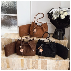 Detail view of suede tote set with ROU JIU logo and floral charm in three colors
