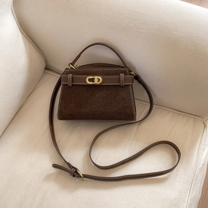 Detailed macro view of dark brown suede crossbody bag with contrast stitching and gold buckle