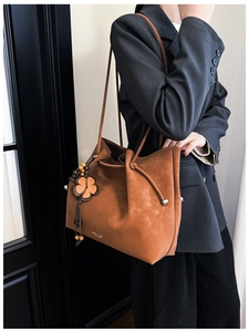 Brown frosted leather tote bag detail with decorative wooden bead and flower charm accessory