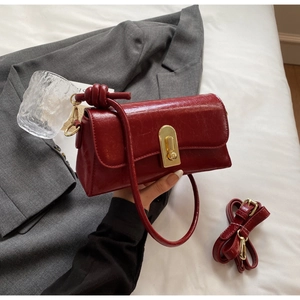 Détail du sac à main en cuir ciré rouge foncé avec fermoir doré et bandoulière nouée