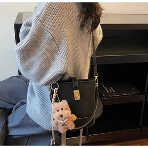 Détail du sac seau noir mat avec boucle dorée et charm d'ours en peluche doux