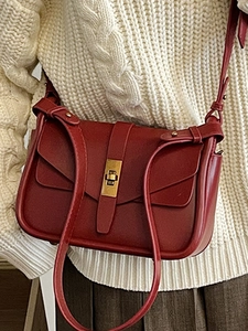 Elegante borsa a tracolla rosso scuro con chiusura a scatto dorata e maglione invernale
