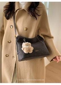 Détail d'un cabas en daim vintage avec breloque ours en peluche et bandoulière en cuir