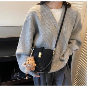 Détail du sac seau en daim noir avec fermoir doré et breloque ours porté par le modèle