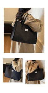 Detail of black checkered tote bag with woven straps and decorative white patch label
