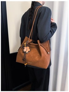 Detail of vintage brown suede tote bag with floral beaded charm and shoulder straps