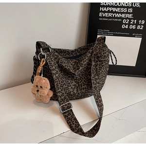 Detail of leopard print canvas tote bag featuring a cute plush bear charm and silver hardware