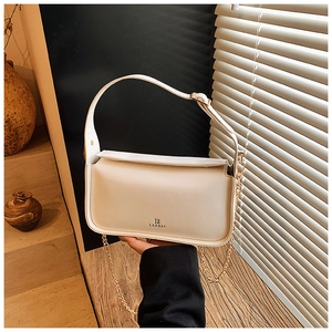 Détail du sac bandoulière en cuir blanc crème avec chaîne dorée et logo de marque