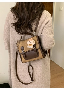 Detail view of retro brown shoulder bag with plush puppy charm and checkered bow accessory