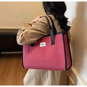 Detailed view of a pink plaid tote bag with black nylon straps worn by a model