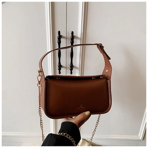 Détail du sac en cuir marron avec bandoulière réglable et chaîne en métal doré chic