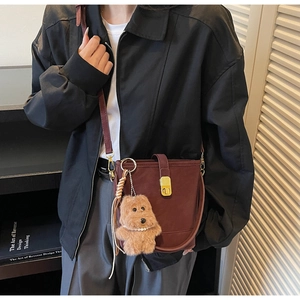 Détail d'un sac seau bordeaux avec fermoir doré et pendentif ours en peluche doux