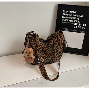 Close-up of leopard print canvas bag with brown teddy bear charm and zipper detail
