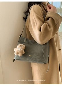 Détail du sac à bandoulière vintage gris-vert avec surpiqûres et pendentif en ours