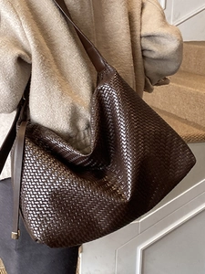Grand sac hobo tressé marron minimaliste porté sur un manteau en tweed beige élégant