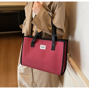 Detail of red checkered tote bag with black straps on a trench coat model