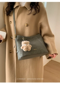 Détail du sac fourre-tout gris-vert en similicuir avec surpiqûres et breloque ourson