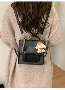 Detail of vintage grey leather mini backpack featuring a plaid ribbon and puppy charm