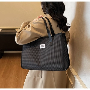 Detail view of large checkered tote bag with black and white pattern and woven handles