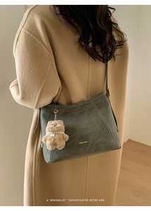 Détail du sac cabas rétro en daim gris avec logo doré et breloque ourson en peluche