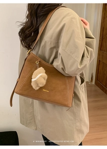Détail du sac cabas en daim caramel avec surpiqûres blanches et charme de perle peluche