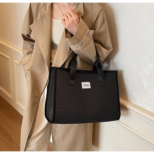 Detail shot of the black checkered tote bag texture with minimalist white logo patch