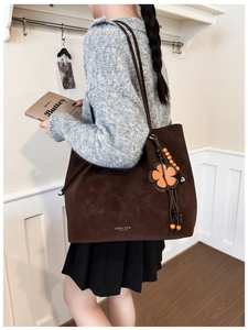 Detail of a brown suede tote bag with leather flower charm and beaded decor