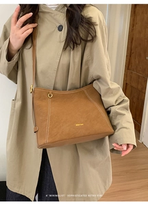 Gros plan sur un sac à bandoulière marron rétro avec surpiqûres blanches et logo doré