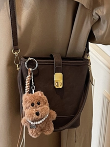 Sac seau vintage marron foncé avec fermoir doré et pendentif ours en peluche sur la bandoulière