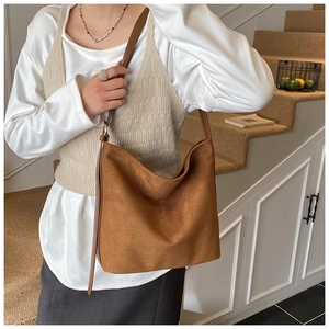 Brown suede hobo bag on shoulder with vintage minimalist style and adjustable strap