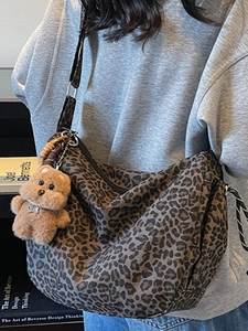 Vintage leopard print canvas shoulder bag with plush bear charm in a crescent shape