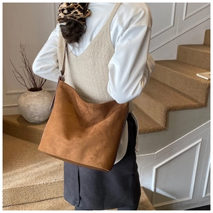 Detail view of the large capacity dark camel suede shoulder bag shown on shoulder