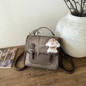 Close-up of retro brown backpack with puppy pendant and decorative plaid ribbon
