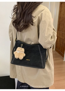Détail du sac cabas en daim noir avec coutures contrastées et breloque ours en peluche
