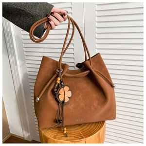 Close-up of brown suede tote bag with flower pendant on a wooden stool