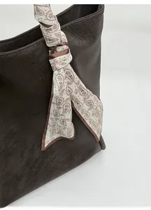 Detail of dark brown tote bag with leather texture and paisley silk scarf charm