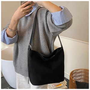 Detail of a black suede hobo shoulder bag with a thin leather strap and metal buckle