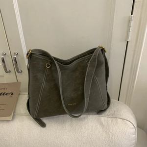 Détail du sac bandoulière gris foncé en similicuir avec surpiqûres blanches et logo doré