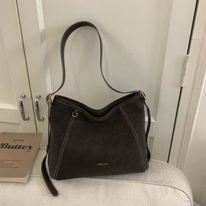 Vue détaillée du sac Hobo en daim marron foncé avec surpiqûres blanches et logo