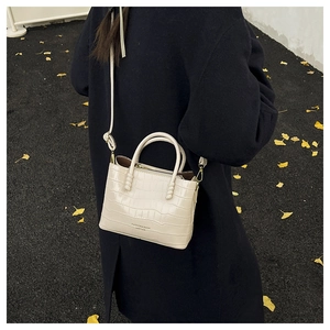 Dettaglio della borsa beige con stampa coccodrillo e una lunga tracolla regolabile