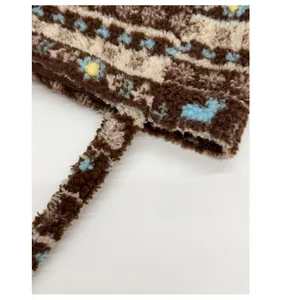 Close-up of reinforced shoulder strap stitching on a floral plush tote bag