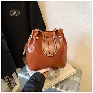 Detailansicht der braunen Bucket Bag mit gewebtem Riemen und goldenen Metallnieten