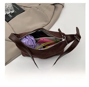 Internal view of brown suede shoulder bag with striped lining and daily essentials inside