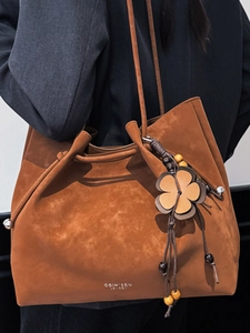 Chic orange suede tote bag for women featuring a drawstring closure and flower charm