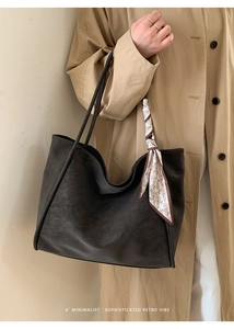 Close-up of retro large-capacity leather tote bag with decorative silk scarf on shoulder strap
