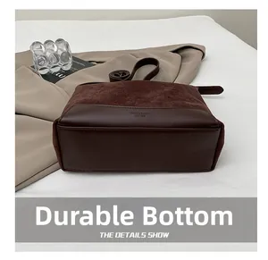 Detailed close-up showing the reinforced wear-resistant base of the brown suede shoulder bag